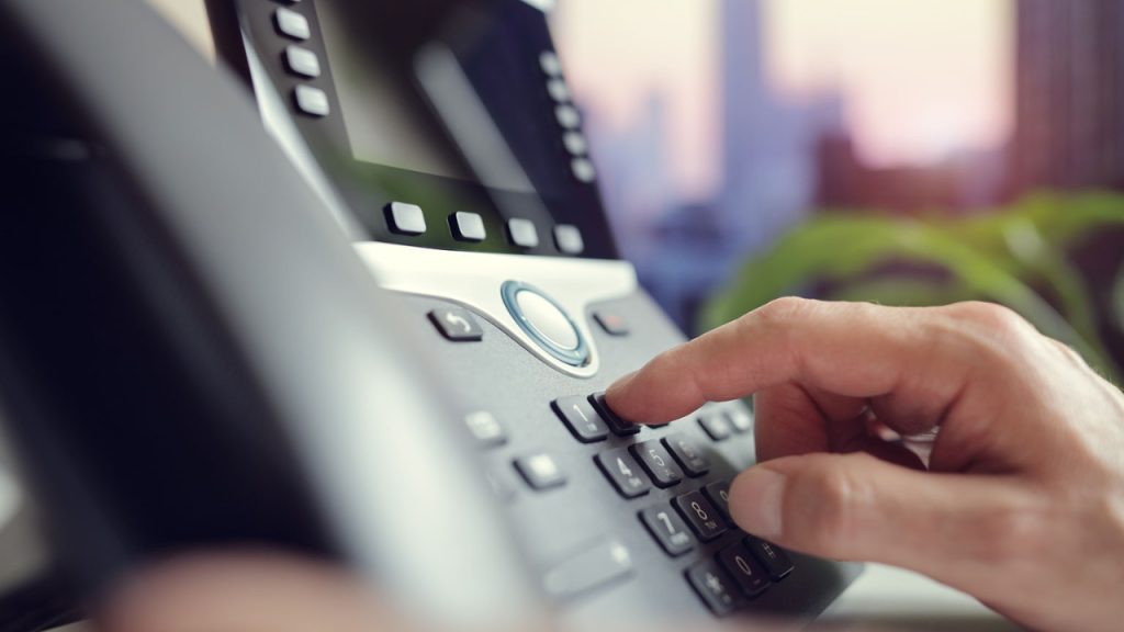 person using office phone: how to forward calls on an nec phone