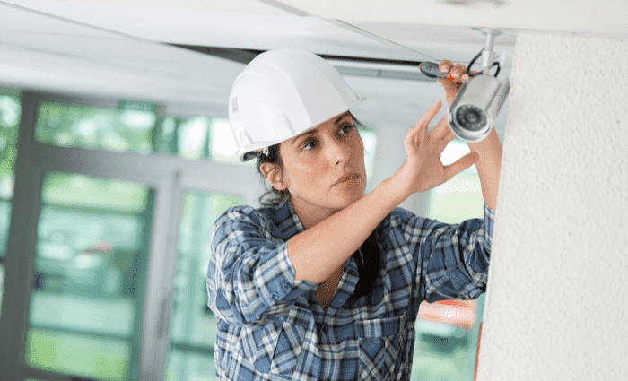 woman installing security camera: insurance benefits of a security camera system