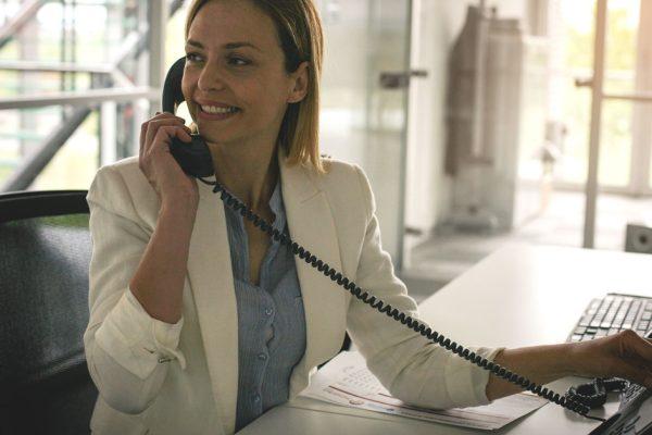 analog vs voip phone: a woman smiling using her business phone