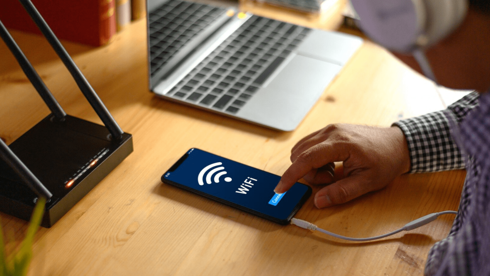 Avoid the Cost of Outages with 4G Backup Internet Connection 2 A person using a smartphone to connect to Wi-Fi near a wireless router and laptop, representing the convenience and reliability of 4G LTE backup for uninterrupted wireless internet connectivity.