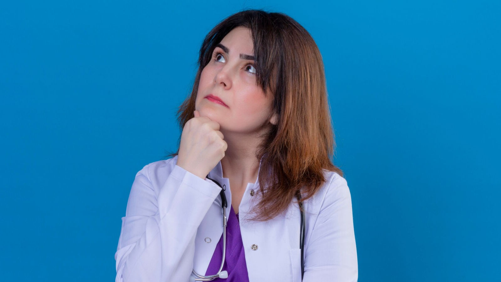 Survive the Summer Rush with the Right Phone Systems for Medical Offices in New England 3 Female doctor with a stethoscope looking up thoughtfully, considering what the best phone system for summer looks like.