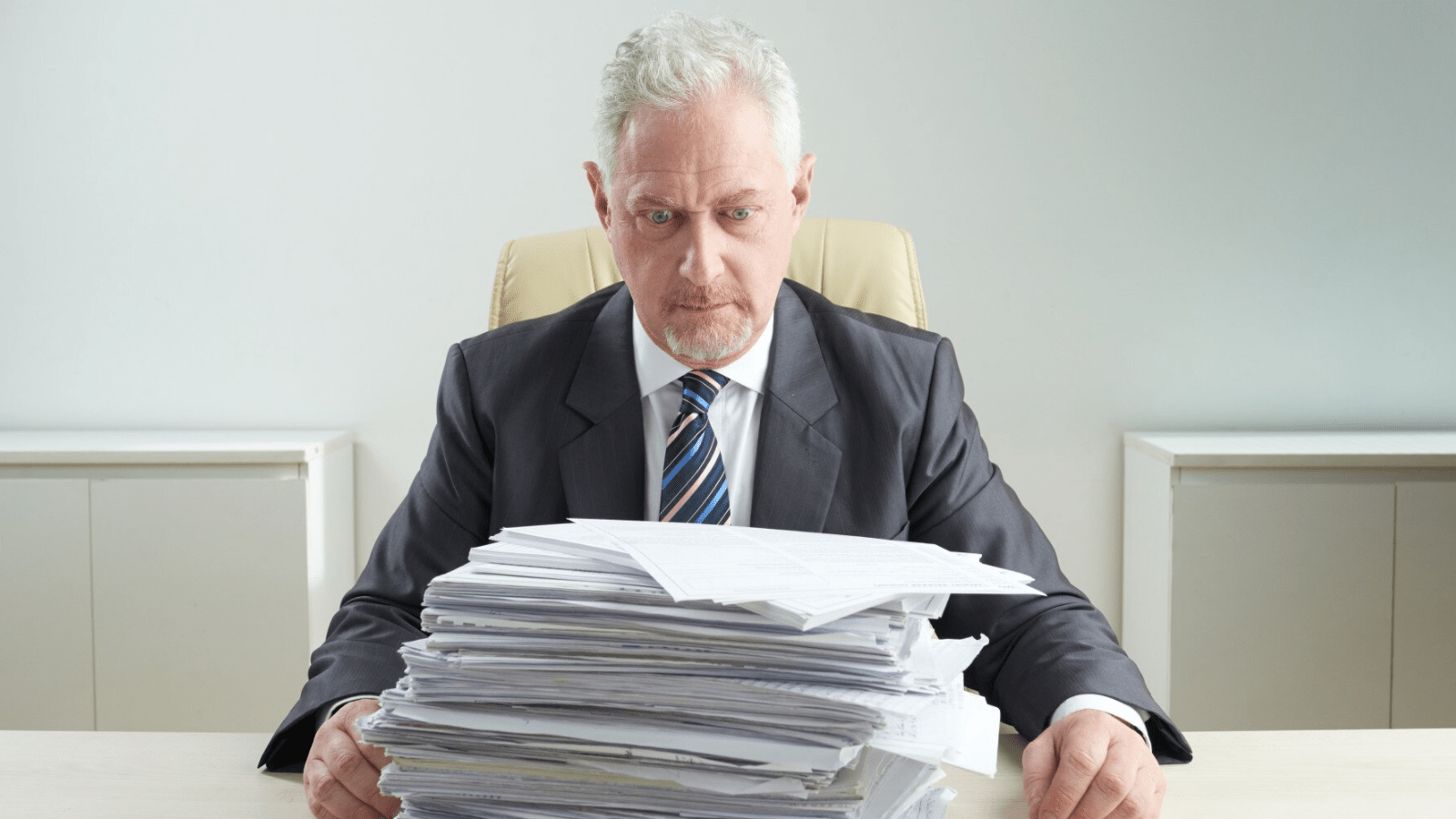 Avoid the Cost of Outages with 4G Backup Internet Connection 1 A concerned businessman staring at a tall stack of bills, highlighting the financial risks of poor network redundancy and the need for reliable 4G Backup systems in business operations.