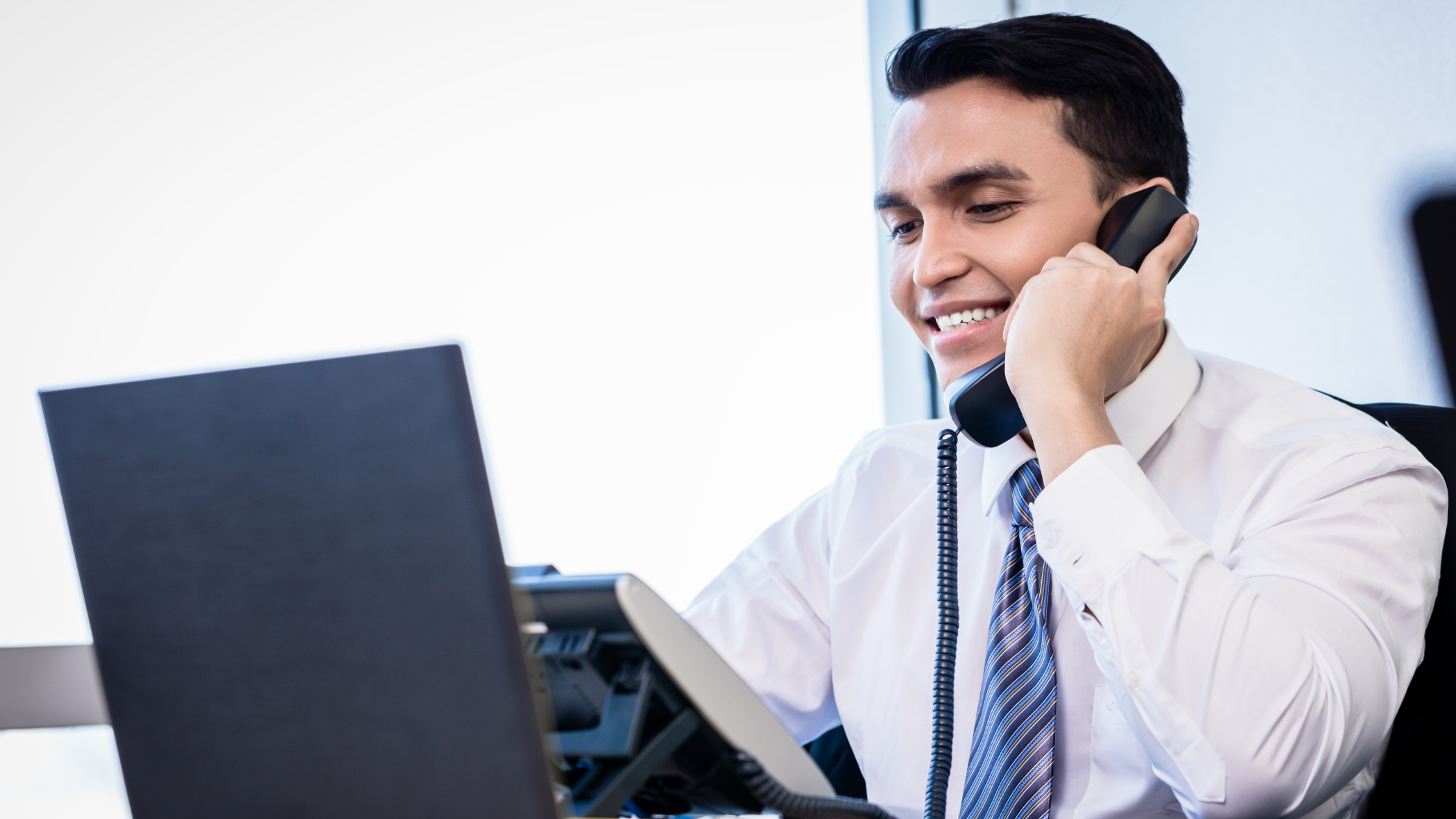 Bank employee handles incoming calls while reviewing financial data, showing how bank phone systems support daily operations.