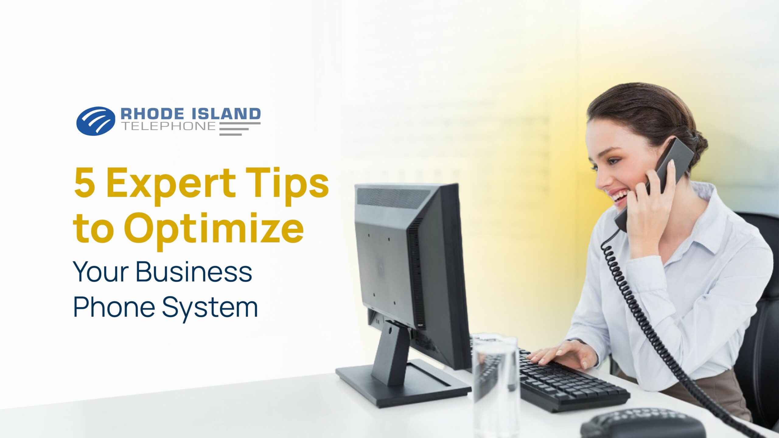 Smiling woman on a corded phone while typing at a desk, promoting tips to optimize your business phone system.