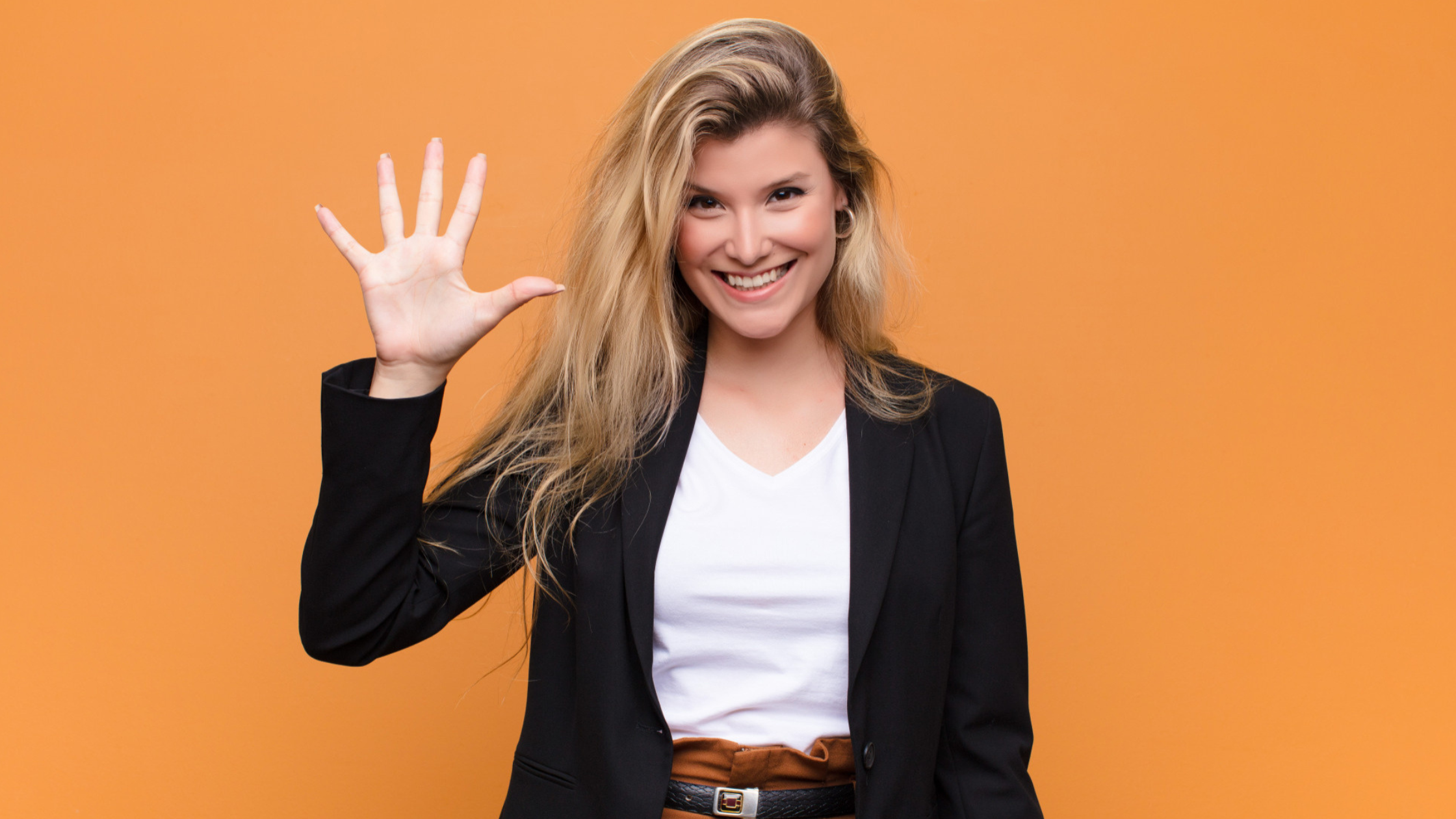 Smiling woman in a blazer holding up five fingers, representing five reasons to switch to cloud phone services.