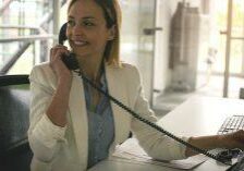 analog vs voip phone: a woman smiling using her business phone